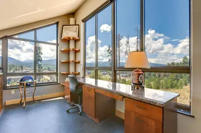 a home office with a desk and large windows at Fraser House with Mtn Views Near Winter Park! in Fraser