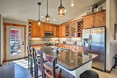 a kitchen with wooden cabinets and a stainless steel refrigerator at Winter Park Condo with Hot Tub and Mountain Views! in Winter Park