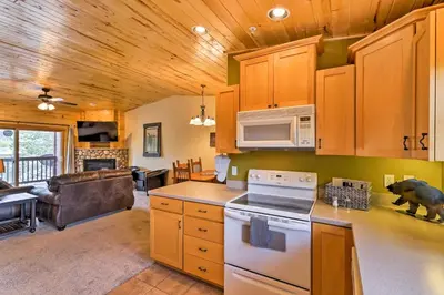 a kitchen with a stove top oven next to a living room at Steps to Grand Lake Condo with Deck and Mtn Views in Grand Lake