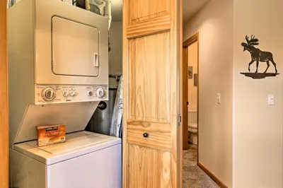 a bathroom with a washer and dryer next to a door at Steps to Grand Lake Condo with Deck and Mtn Views in Grand Lake