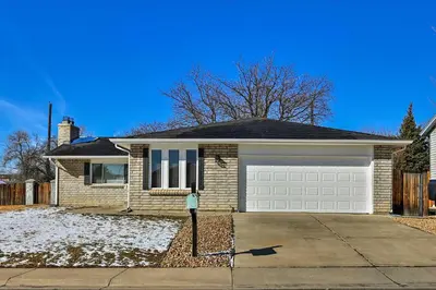 a white brick house with a parking meter in front of it at Arvada Home with Deck and Game Room Near Olde Town! in Arvada
