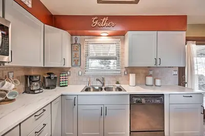 a kitchen with white cabinets and a sink at Arvada Home with Deck and Game Room Near Olde Town! in Arvada