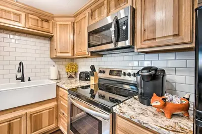 a kitchen with wooden cabinets and a stove top oven at 11 Mi to Denver Zoo Lakewood Studio with Fire Pit! in Lakewood