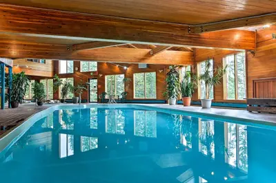 a swimming pool in a house with wooden ceilings and windows at Mtn-View Gem with Community Perks in Silverthorne! in Silverthorne