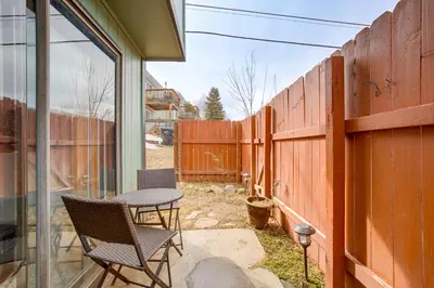 a patio with two chairs and a table and a fence at Near Red Rocks, Hiking and Skiing Kittredge Condo! in Kittredge