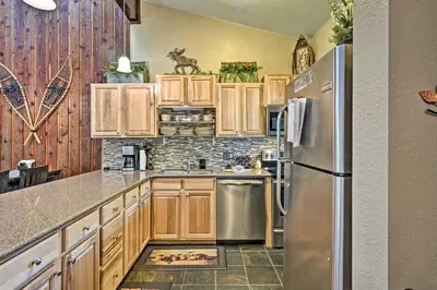 a kitchen with wooden cabinets and a stainless steel refrigerator at Condo with Pool and Hot Tub - Walk to DT Winter Park! in Winter Park