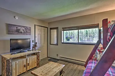 a living room with a flat screen tv and a staircase at Condo with Pool and Hot Tub - Walk to DT Winter Park! in Winter Park