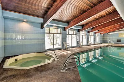 a large swimming pool with a tub in a room at Condo with Pool and Hot Tub - Walk to DT Winter Park! in Winter Park