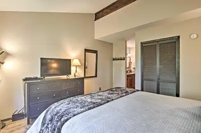 a bedroom with a large bed and a television at Condo with Pool and Hot Tub - Walk to DT Winter Park! in Winter Park