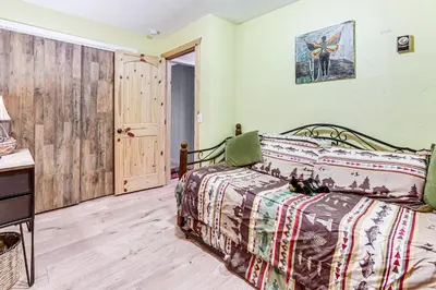 a bedroom with a bed and a wooden floor at Balcony, Fire Pit and Grill Grand Lake Retreat! in Grand Lake