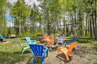 a group of colorful chairs sitting around a campfire at Balcony, Fire Pit and Grill Grand Lake Retreat! in Grand Lake