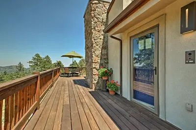 a wooden deck with a table and an umbrella at 12 Mi to Red Rocks Morrison Home with Deck in Morrison