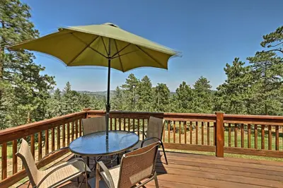 a table and chairs on a deck with an umbrella at 12 Mi to Red Rocks Morrison Home with Deck in Morrison