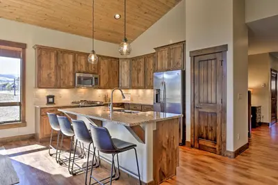 a kitchen with wooden cabinets and a large island with bar stools at Mtn-View Fraser Home with Hot Tub - Near Skiing! in Fraser
