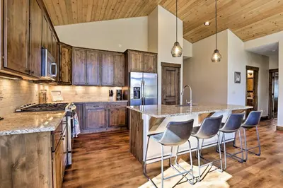a kitchen with wooden cabinets and a large island with bar stools at Mtn-View Fraser Home with Hot Tub - Near Skiing! in Fraser