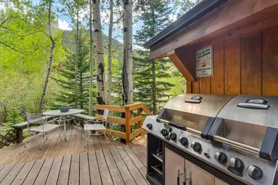 a patio with a grill and a table on a deck at Cabin on Clear Creek A Hobbits Retreat! in Black Hawk