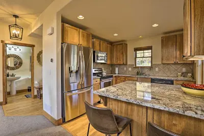 a kitchen with a stainless steel refrigerator and wooden cabinets at Winter Park Area Cabin, Hot Tub and Mountain Views! in Fraser