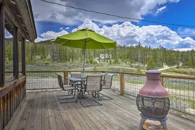 a patio with a table and an umbrella on a deck at Updated Cabin with Hot Tub about 11 Mi to Winter Park! in Tabernash