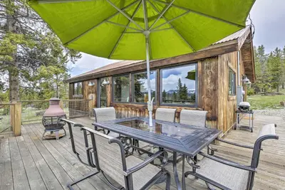 a wooden deck with a table and chairs with an umbrella at Updated Cabin with Hot Tub about 11 Mi to Winter Park! in Tabernash