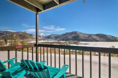 a porch with blue chairs and snow covered mountains at Grand Lake Condo Best Lake View and Panoramic Deck in Grand Lake