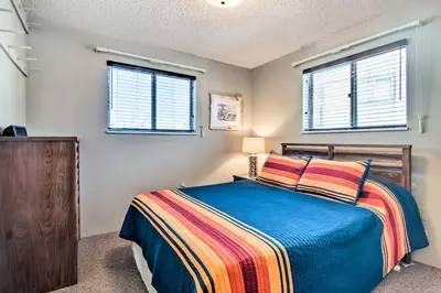 a bedroom with a bed and two windows at Grand Lake Condo Best Lake View and Panoramic Deck in Grand Lake
