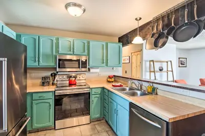 a kitchen with green cabinets and a stainless steel refrigerator at Grand Lake Condo Best Lake View and Panoramic Deck in Grand Lake
