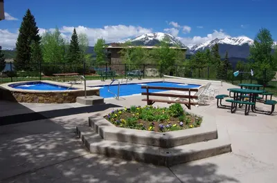 a pool with a table and benches and a picnic table with mountains at Mtn-View Condo with Hot Tub Access in Dillon! in Dillon