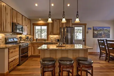 a kitchen with wooden cabinets and a large island with bar stools at Hot Tub! Family Gem on Snake River in Keystone! in Keystone