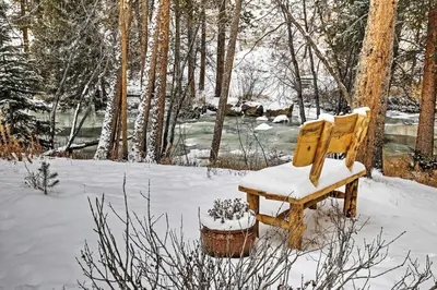 a wooden chair sitting in the snow in a forest at Hot Tub! Family Gem on Snake River in Keystone! in Keystone