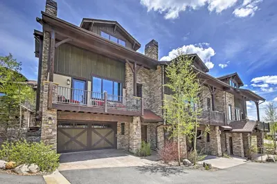 a large stone house with a balcony and a garage at Lavish Fraser Townhome with Deck and Mountain Views! in Fraser
