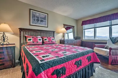 a bedroom with a bed with a pink comforter at 1 Mi to Granby Ranch Cozy Condo with Fireplace in Granby