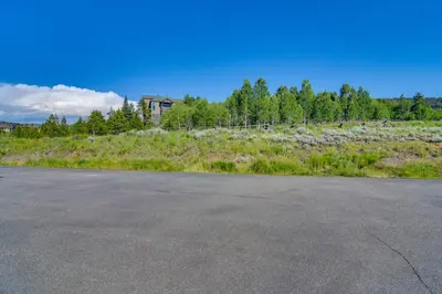 an empty road in a field with a house in the background at 1 Mi to Granby Ranch Cozy Condo with Fireplace in Granby