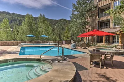 a swimming pool with a table and an umbrella at Keystone Ski Condo with Mtn View - Walk to Gondola! in Keystone