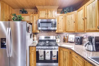 a kitchen with wooden cabinets and a stainless steel refrigerator at 2 Mi to Rocky Mountain Natl Park Cabin with Views in Grand Lake