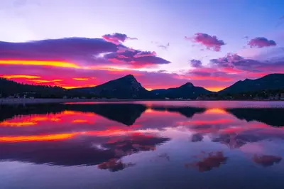 a sunset over a lake with mountains in the background at Deer Mountain 28B condo in Estes Park
