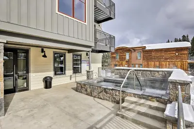 a house with a hot tub on a patio at Modern Winter Park Ski Condo Near the Ski Shuttle! in Winter Park