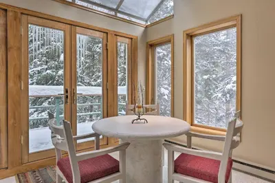 a dining room with a table and chairs and windows at Ski-InandSki-Out Winter Park Condo with Pool Access! in Winter Park
