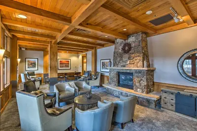 a living room with a stone fireplace and chairs at Cozy Ski-InandSki-Out Winter Park Resort Condo! in Winter Park