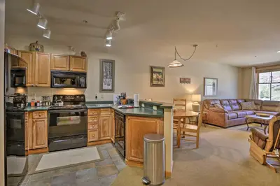 a kitchen with wooden cabinets and a living room at Cozy Ski-InandSki-Out Winter Park Resort Condo! in Winter Park