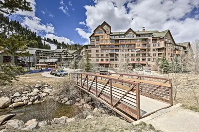 a bridge over a river in front of a large building at Cozy Ski-InandSki-Out Winter Park Resort Condo! in Winter Park