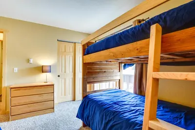 a bedroom with two bunk beds and a desk at Cozy Winter Park Condo with Hot Tub and Shuttle! in Winter Park
