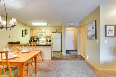 a kitchen and dining room with a wooden table and chairs at Cozy Winter Park Condo with Hot Tub and Shuttle! in Winter Park