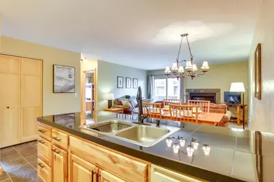 a kitchen with a sink and a living room at Cozy Winter Park Condo with Hot Tub and Shuttle! in Winter Park