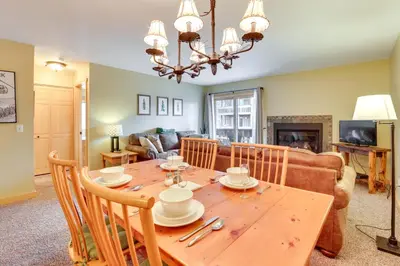 a dining room and living room with a wooden table at Cozy Winter Park Condo with Hot Tub and Shuttle! in Winter Park