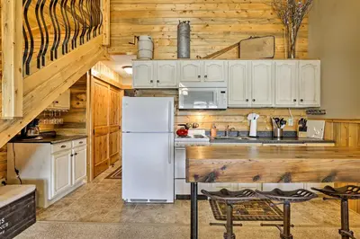 a kitchen with a white refrigerator and wooden cabinets at Granby Condo with Pool Access, Near Hiking and Skiing! in Granby