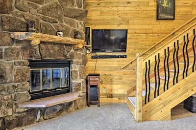a living room with a stone fireplace and a tv at Granby Condo with Pool Access, Near Hiking and Skiing! in Granby