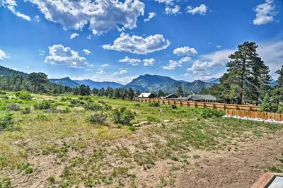 a field with a fence and mountains in the background at Estes Park Mountain-View Retreat 3 Miles to RMNP! in Estes Park