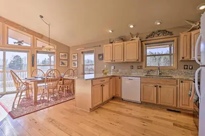 a kitchen with wooden cabinets and a table and a dining room at Grand Lake House with Mountain Views, Deck! in Grand Lake