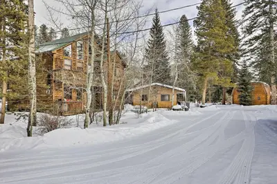 a snow covered road in front of a log cabin at Direct Beach Access Grand Lake Cabin with Deck! in Grand Lake