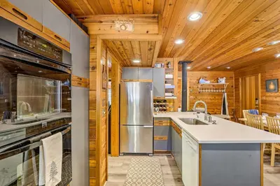 a kitchen with wooden ceilings and a stainless steel refrigerator at Tranquil Dumont Home with Creek and Mtn Views! in Dumont